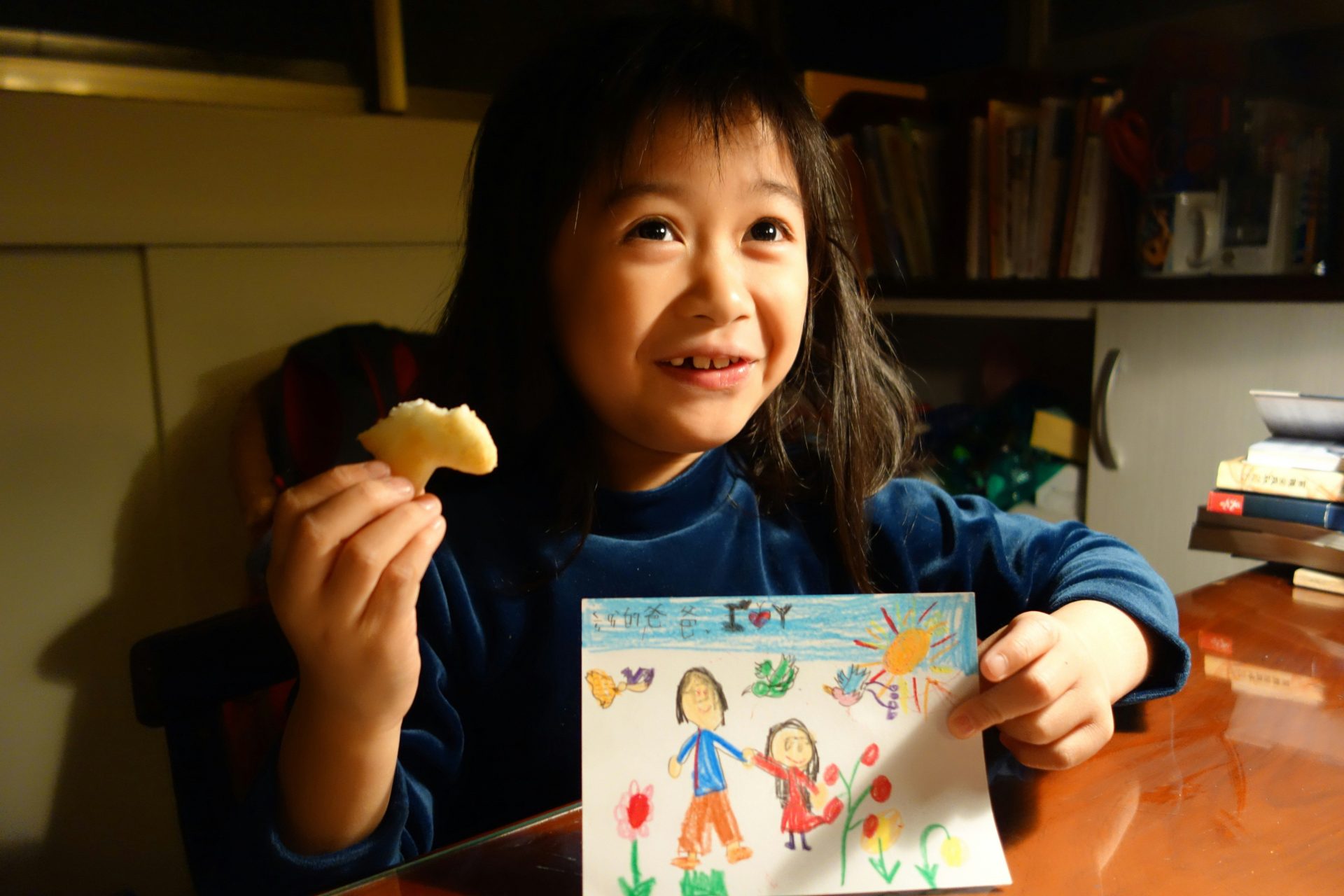 Young girl holds drawing and snack