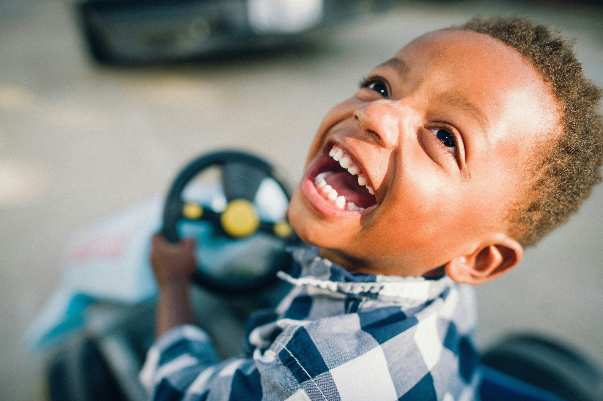 A young boy smiles while driving a toy car