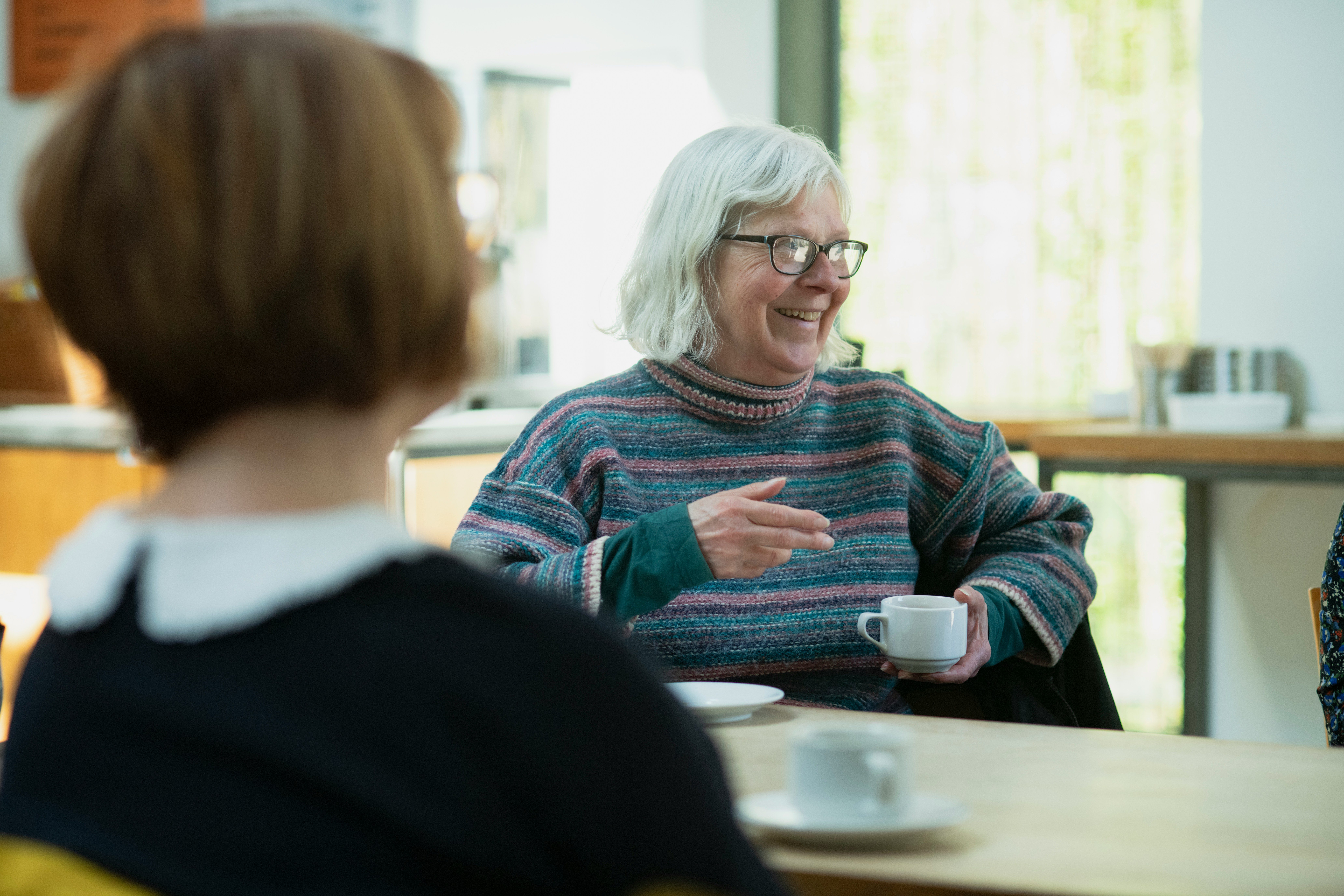 a woman sitting at a table with a cup of coffee